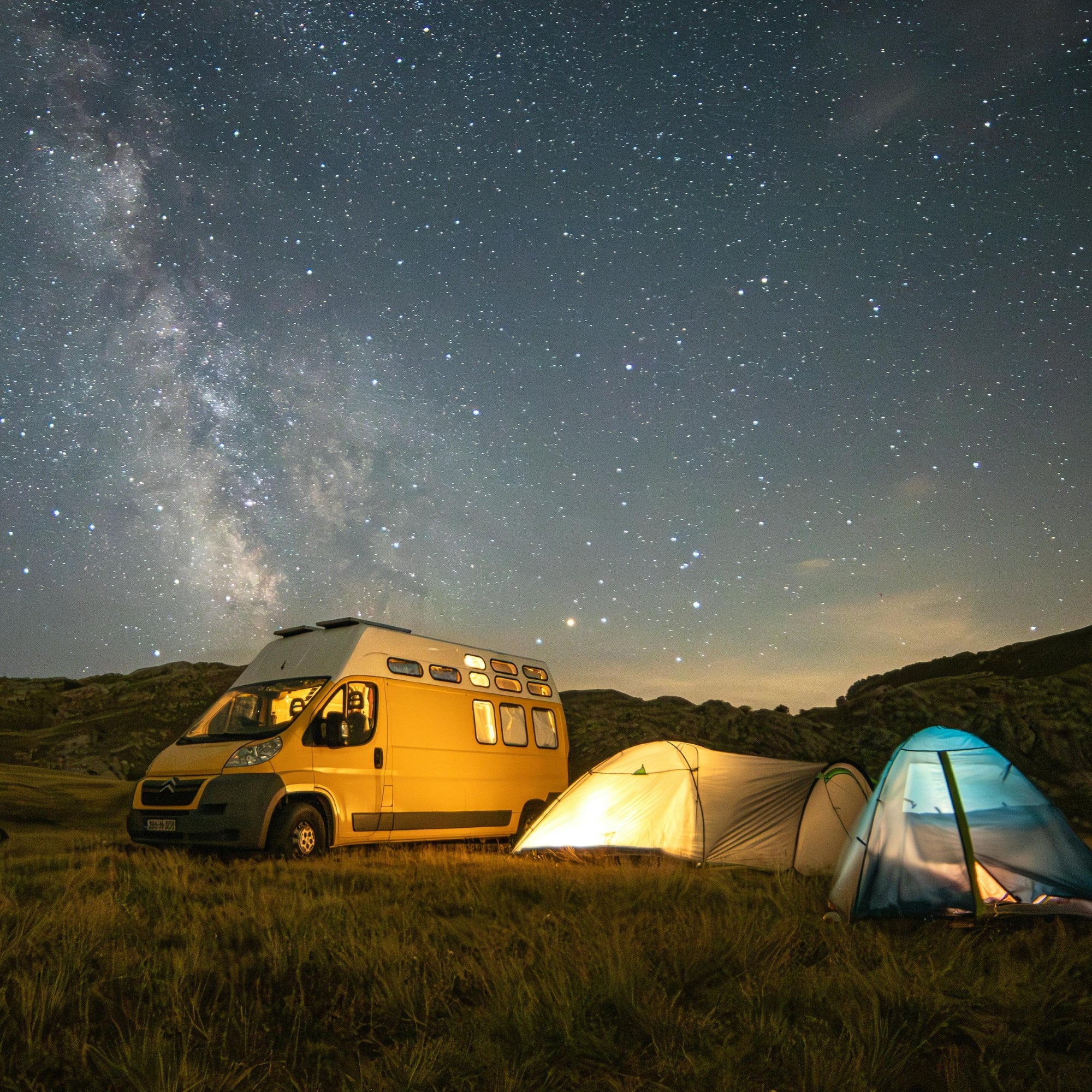Campervan und beleuchtete Zelte unter dem Sternenhimmel beim Camping – Blizz Dog, Vanlife mit Hund